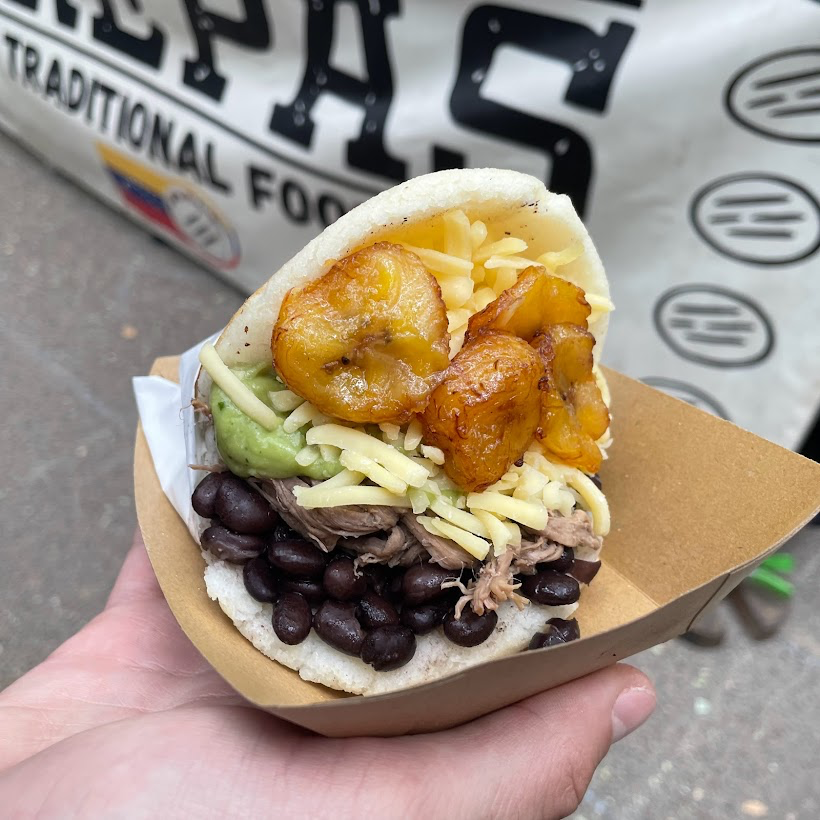An arepa filled with beans, pulled beef, cheese and fried plantain